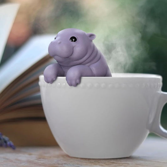 Purple baby hippo tea infuser in a white mug with a blurred background