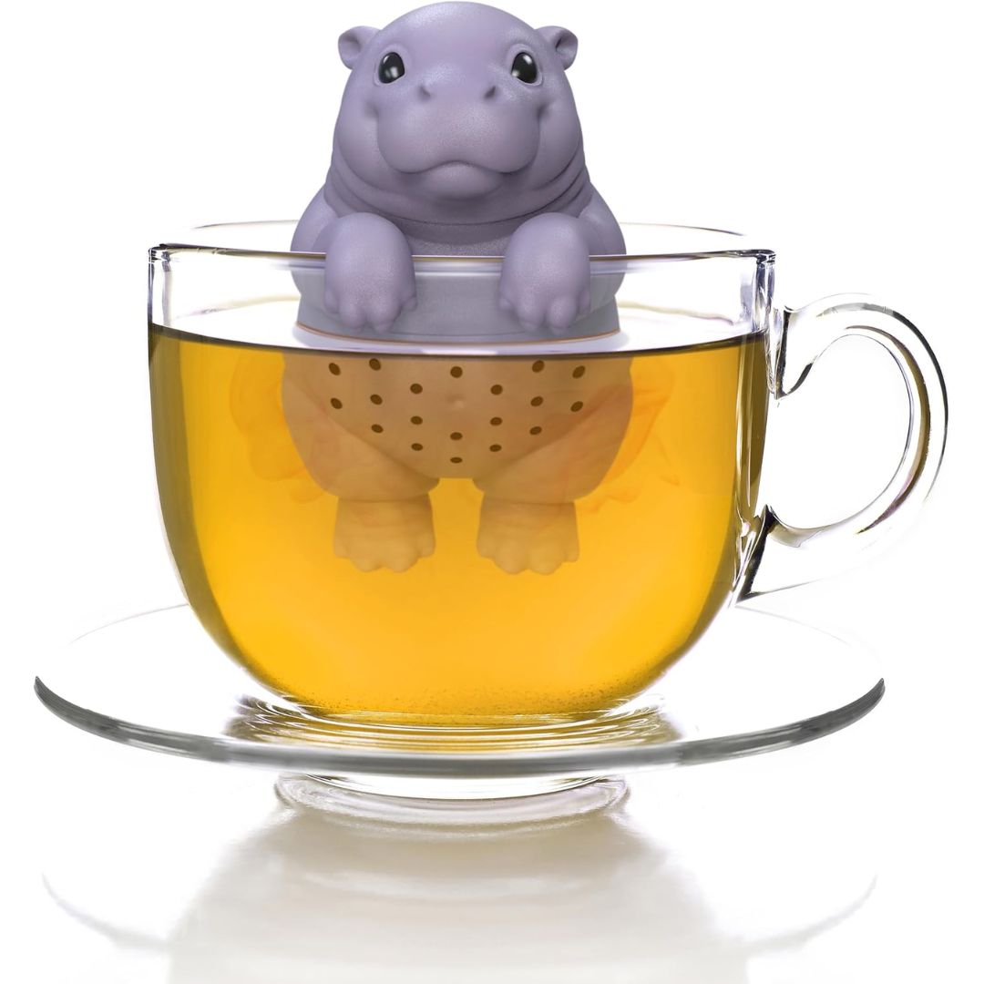 Purple baby hippo-shaped tea infuser in a glass of tea on a white background