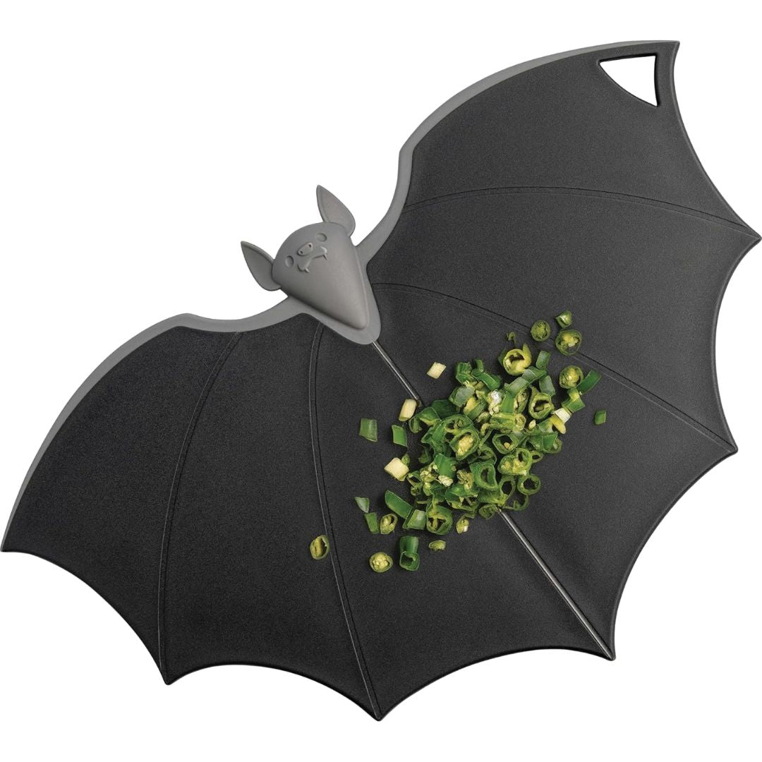 Black bat-shaped chopping board with spring onions on a white background