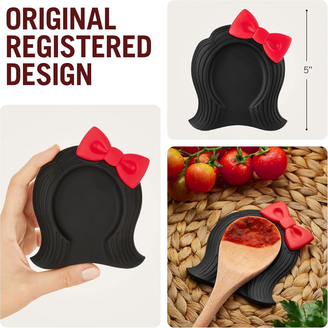Black silicone spoon rest with red bow on a white background, held by a hand, and used with tomatoes and a wooden spoon.