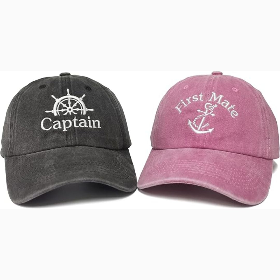Two baseball caps, one black with 'Captain' and the other pink with 'First Mate', on a white background.