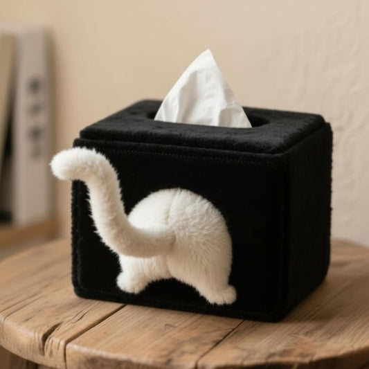 Black tissue box cover with a cat's bottom and tail design on a wooden surface.