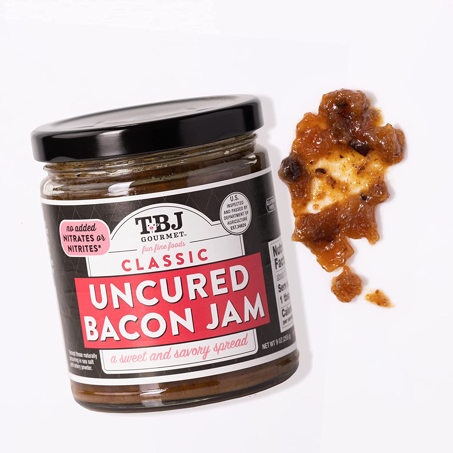 A glass jar of bacon jam with a small amount of bacon jam smeared next to the jar.