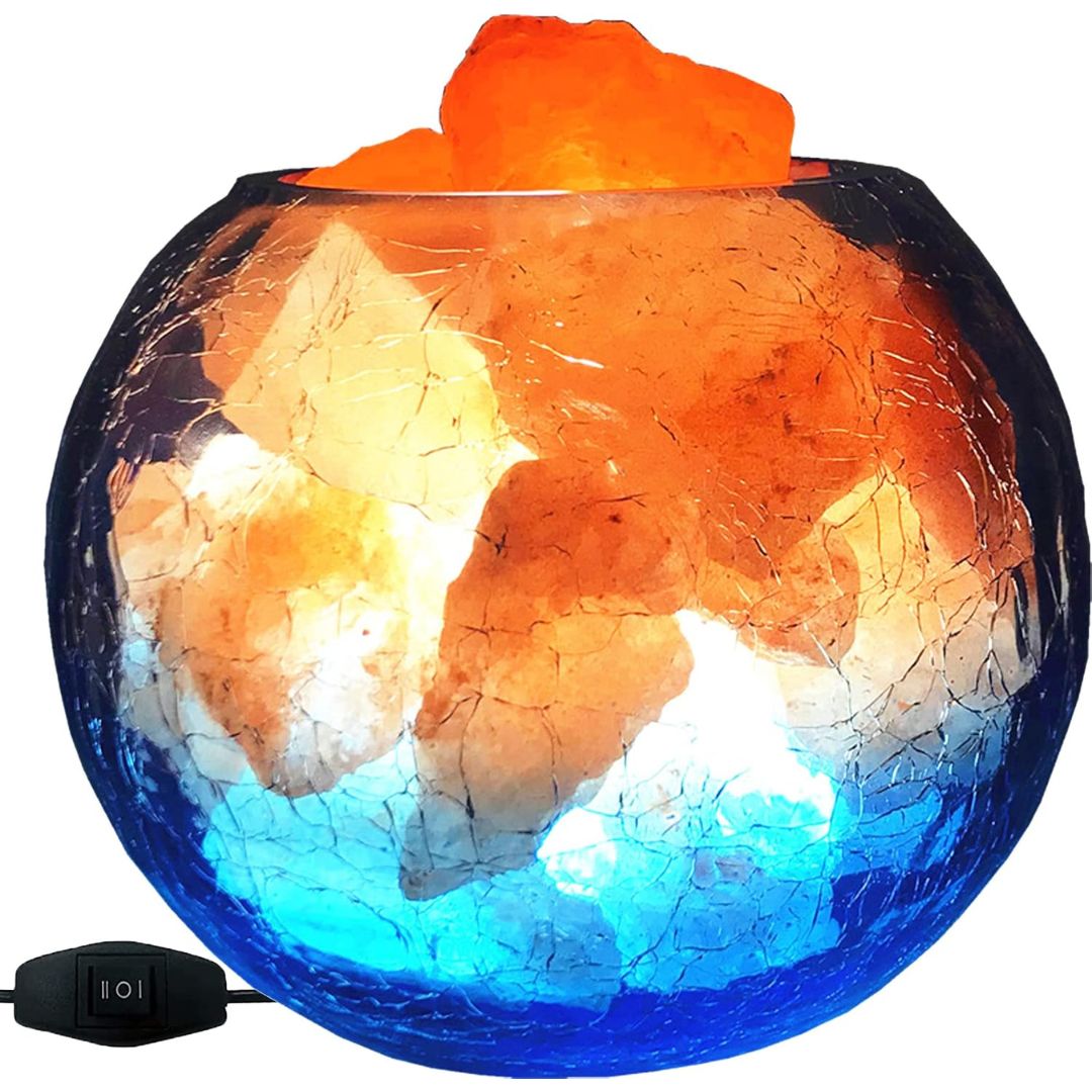 A spherical salt lamp with a crackled glass bowl, filled with orange and white salt stones and glowing with blue light. A black power switch with a cord is visible in the bottom left corner, set against a plain white background.