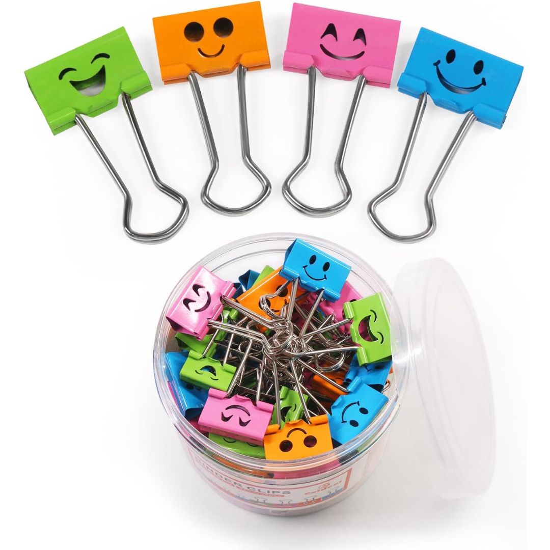 Five colorful smiley-face paperclips in green, orange, pink, blue, and light blue are displayed above a clear plastic jar filled with additional paperclips in assorted colors. The clips have metal spring clips and black printed smiley faces on their plastic heads.