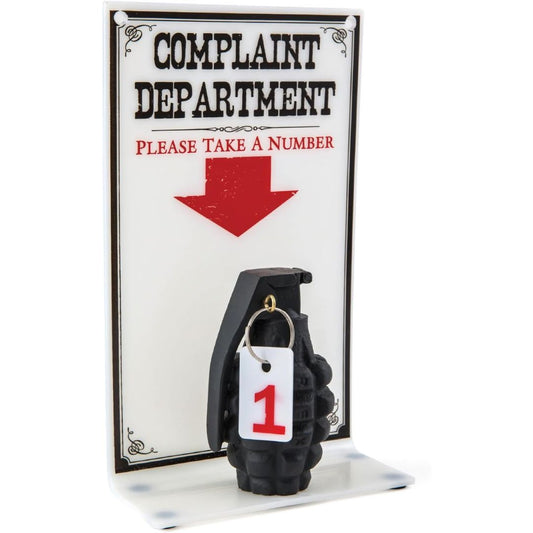 Black hand grenade with a number tag in front of a 'Complaint Department' sign.