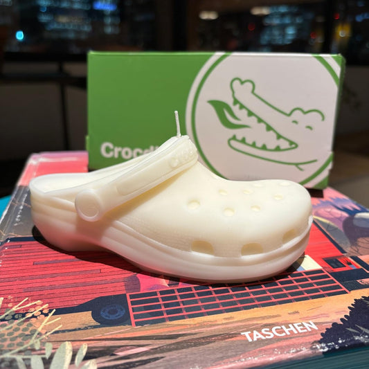 White croc shoe candle on a colorful book with a Crocs candle gift box in the background