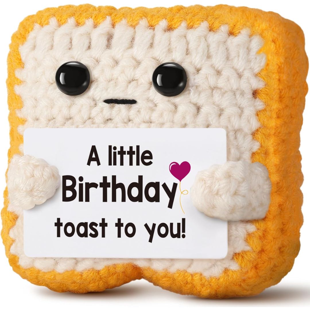 Crocheted plush toy resembling a slice of bread with a birthday message tag on a white background