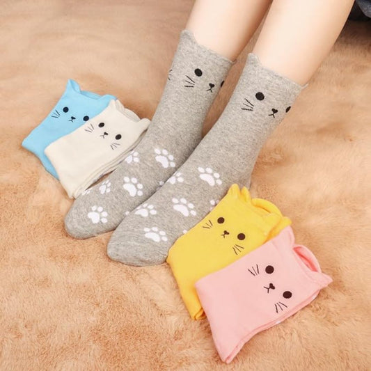Cute cat shaped socks in various colors with a pair of legs wearing a grey pair.