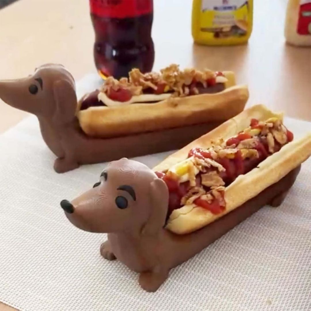 Two dog-shaped hot dog holders with a hot dog inside each one on a table.