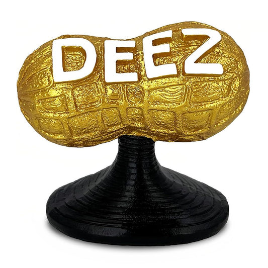 Gold 'DEEZ' peanut-shaped statue on a black stand against a white background