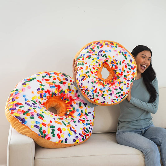 A smiling woman is on a large with two donut shaped pillows.