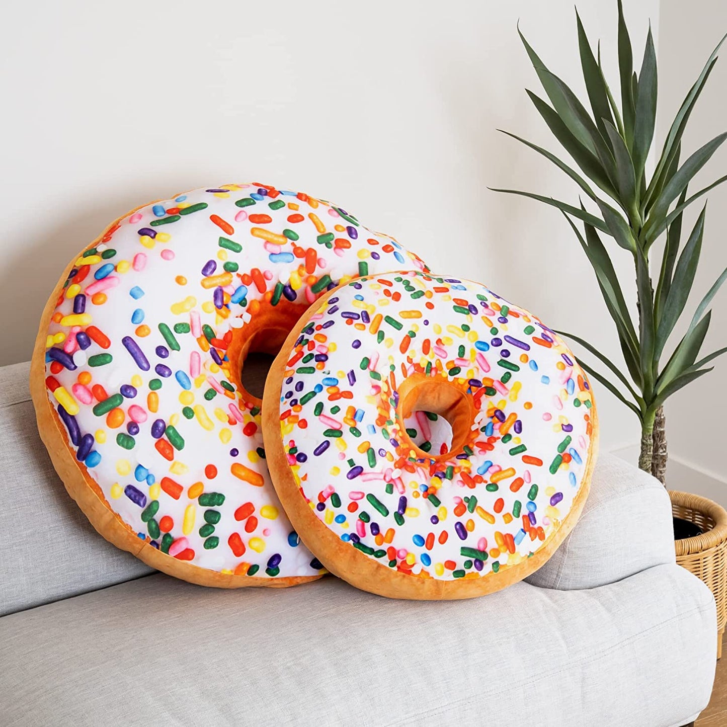 Two different sized donut shaped pillows are on a lounge.