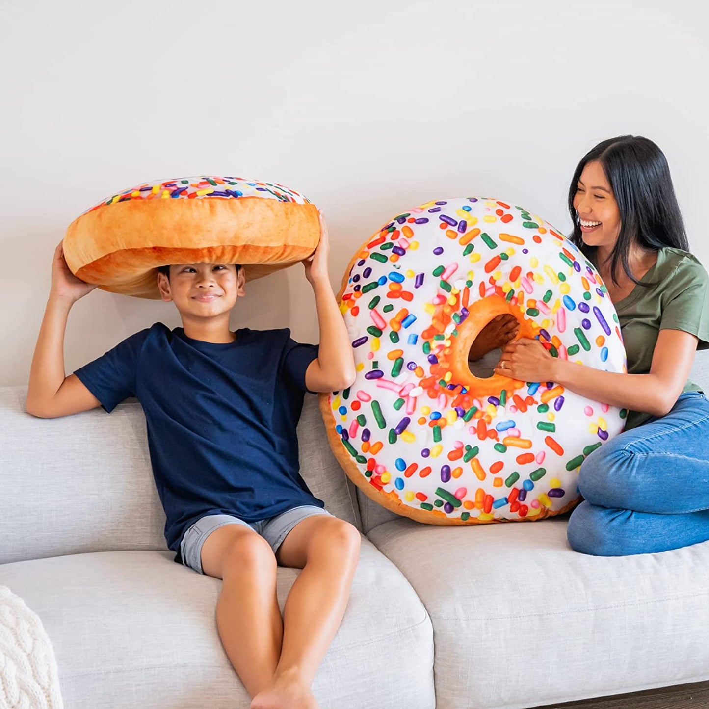 A child and woman are playing with two donut shaped pillows.