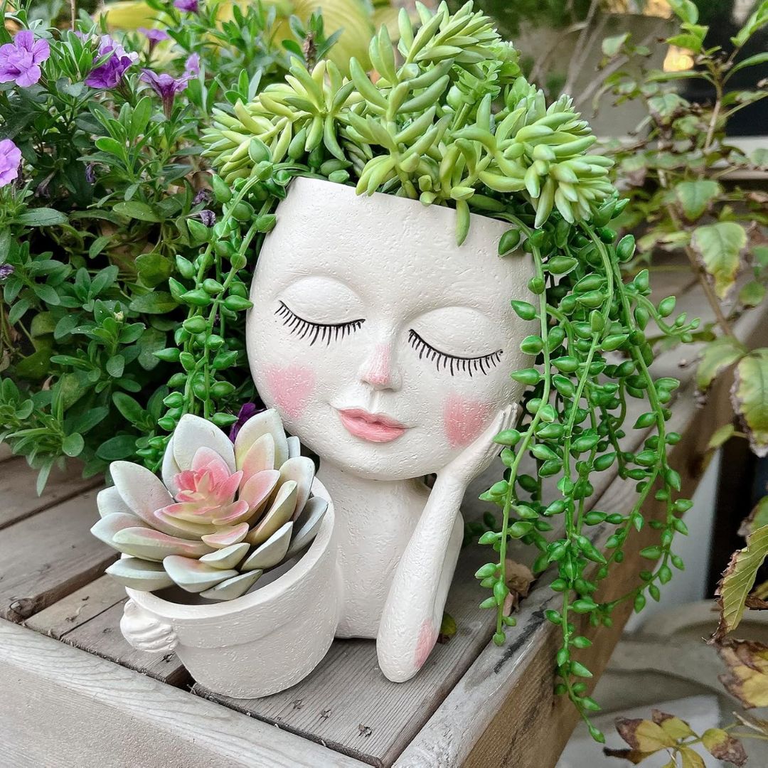A plant pot shaped like a woman's head and shoulders with a succulent growing out of the top that looks like hair