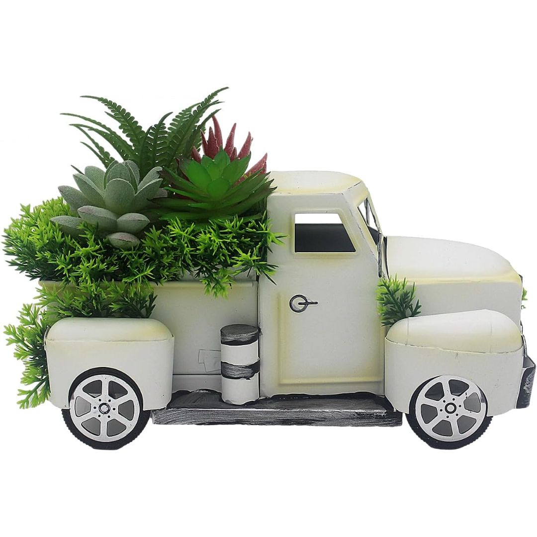 A decorative vintage-style pickup truck planter in off-white, filled with artificial green succulents and ferns, shown on a plain white background.