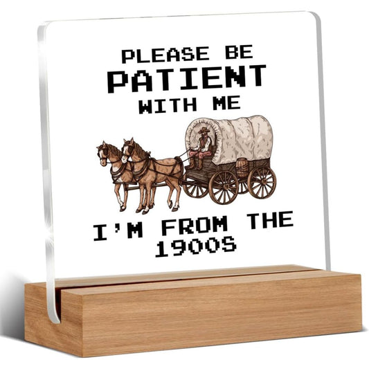 A funny glass and wood sign with text reading 'Please be patient with me I'm not the 1900s' on a white background