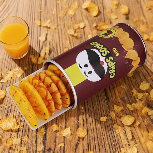 Socks that look like crispy snacks in a branded container with a glass of orange juice on a wooden surface