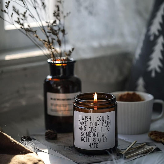A funny get well candle with text on it saying, 'I wish I could take your pain and give it to someone we both really hate' on a rustic table with decorations