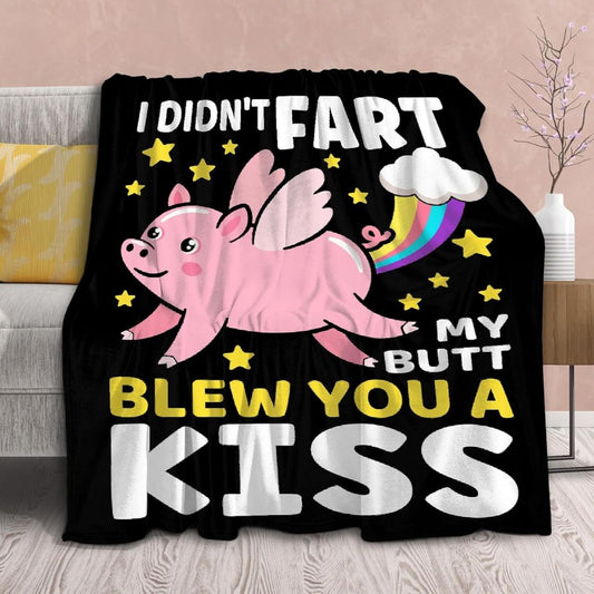 A black blanket featuring a pink flying pig with text that reads "I didn't fart my butt blew you a kiss" in a lounge setting.