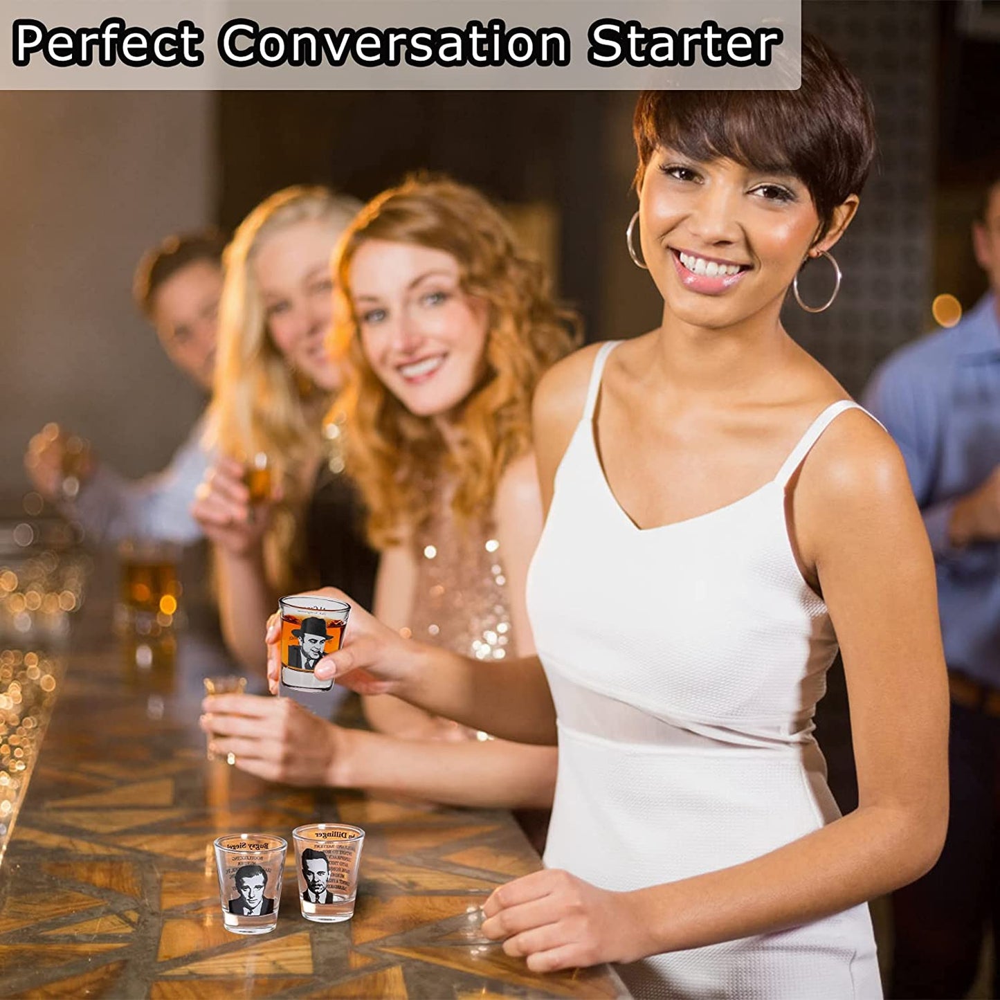 Three woman and a man are at a bar holding gangster shot glasses