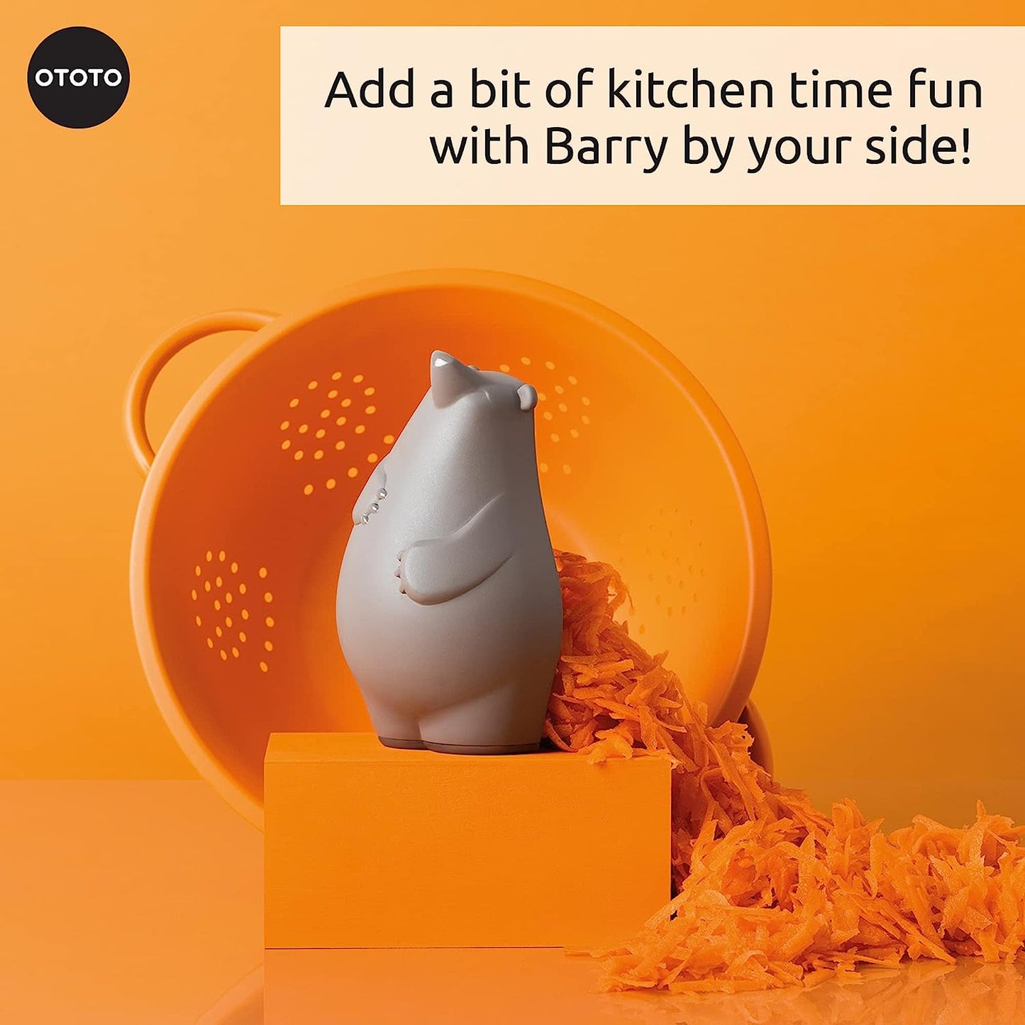 A kitchen grater shaped like a brown bear is sitting on an orange block next to shredded carrot.