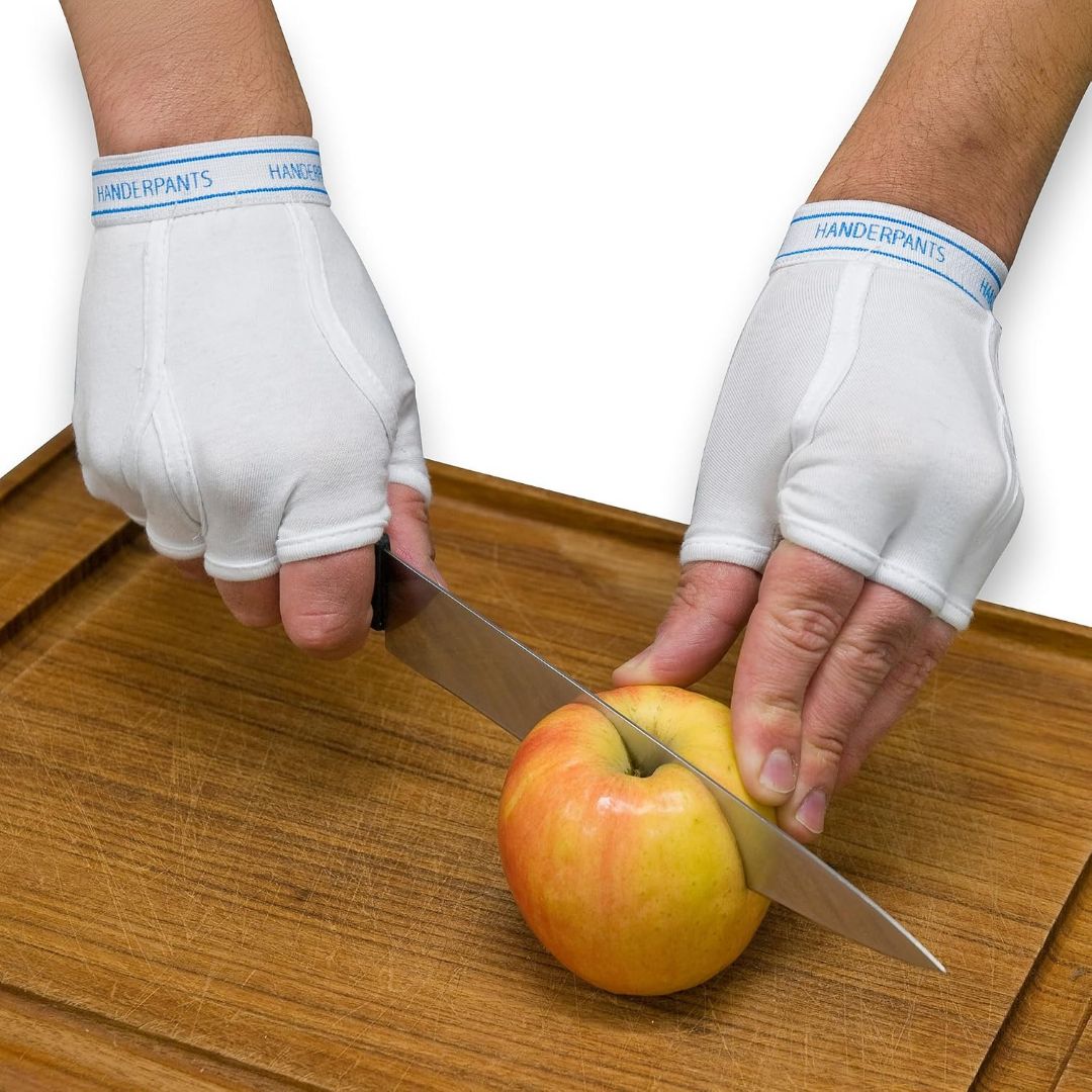 White fingerless Handerpants underwear gloves worn while slicing an apple on a wooden cutting board