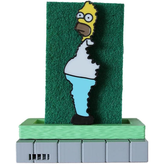 A Simpsons-themed kitchen sponge featuring Homer Simpson standing in front of a green textured panel, mounted on a light green and gray base against a plain white background.