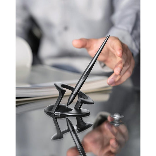A hover pen with stand on a shiny desk with a hand about to pick up the pen.