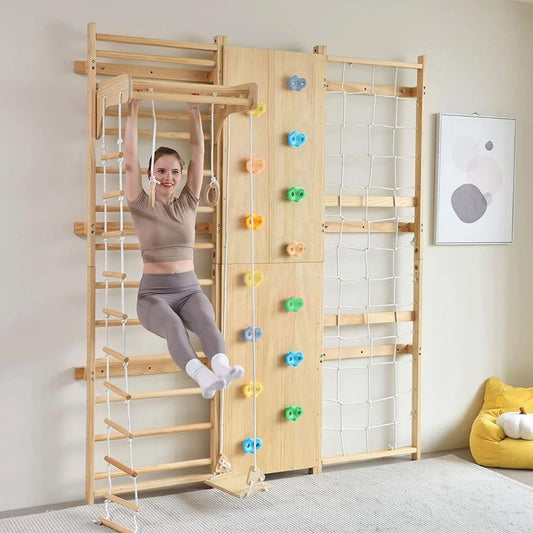 Woman playing on a wooden climbing indoor wall gym with colorful holds in a room.