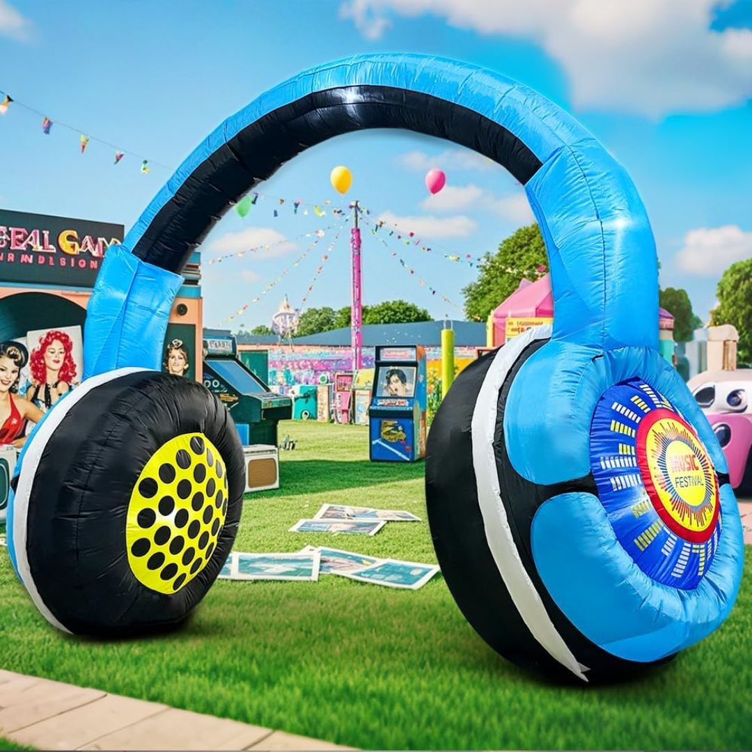 Inflatable headphones with colorful designs on a grassy field with fairground in the background