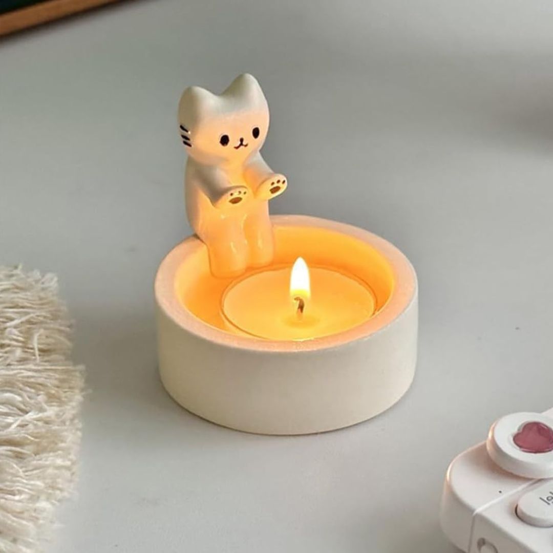 Cat shaped candle holder that looks like the cat is warming its hands by the tea light candle flame