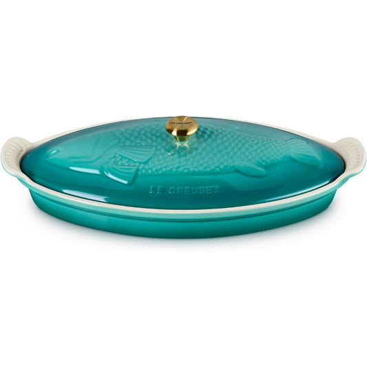 Le Creuset Riviera fish-shaped stoneware baker with turquoise lid and gold knob on a white background