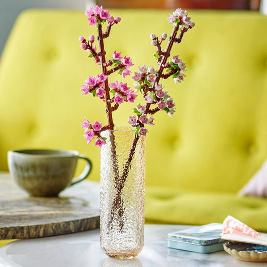 Decorative vase with Lego cherry blossom flowers on a table with a yellow chair in the background