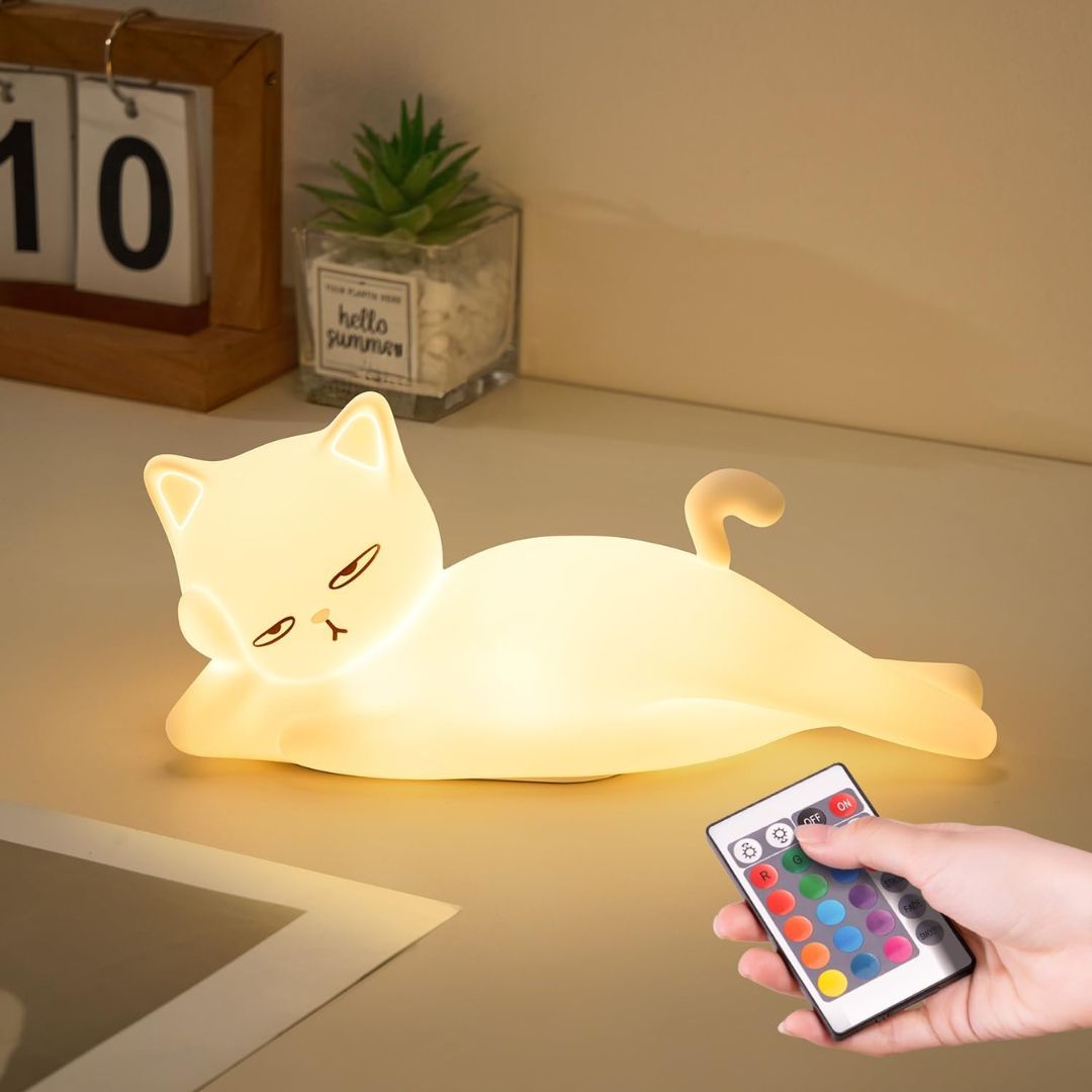 Glowing white cat night light lying flat with remote control