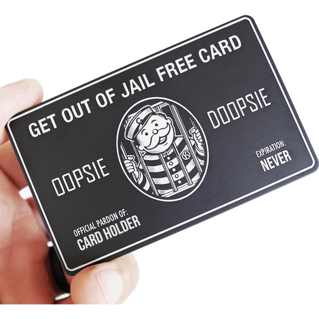 A novelty jailhouse card held in a hand against a white background. The card is black with white text reading 'GET OUT OF JAIL FREE CARD', 'OOPSIE', and 'OFFICIAL PAROLE OF: CARD HOLDER', plus a cartoon parole officer illustration.