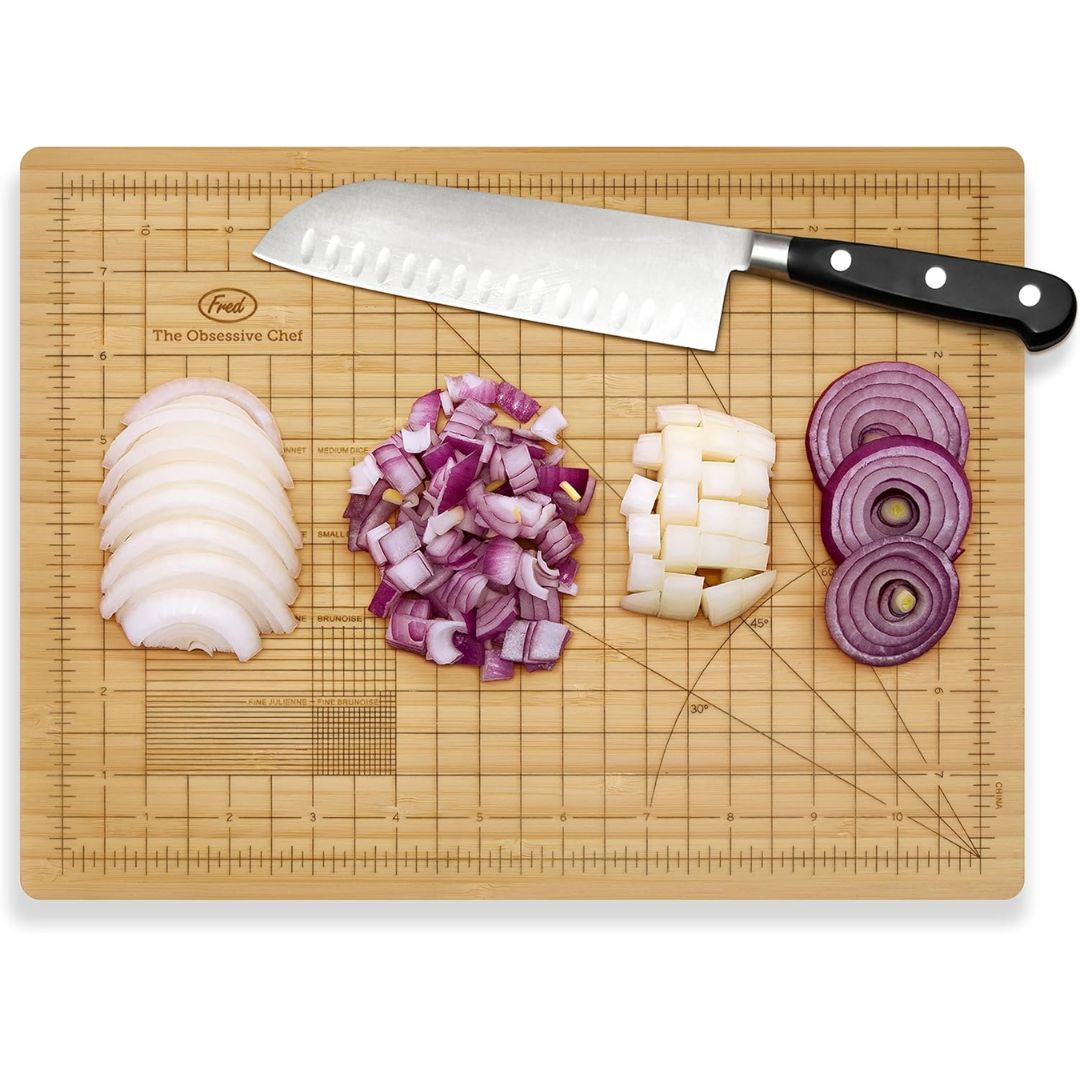 Wooden bamboo measuring cutting board with chopped onions and a knife on a white background