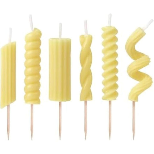 Set of yellow pasta shaped candles with wooden sticks against a white background