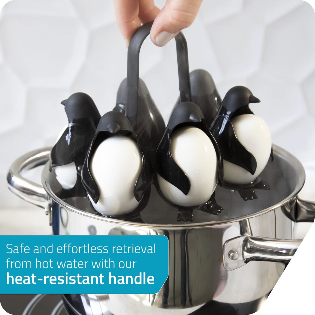 Egg cooker shaped like penguins holding eggs being placed into a silver pot of water.