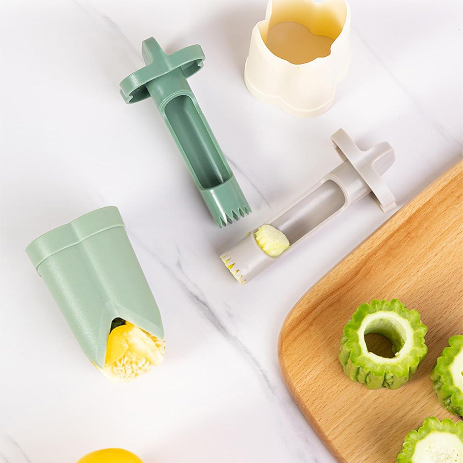 A pepper seed corer remover as it cores okra and a yellow pepper on a wooden board, with cored okra pieces and a white corer on a marble counter.