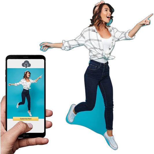 A hand holds a smartphone showing a custom apparel mockup screen, while a woman in a white plaid shirt, dark jeans, and white sneakers jumps beside it on a plain white background.