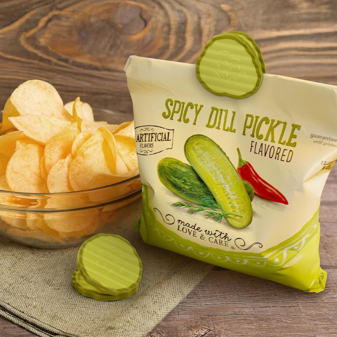 Spicy dill pickle flavored chips with packaging sealed with a pickle shaped bag clip on a wooden surface