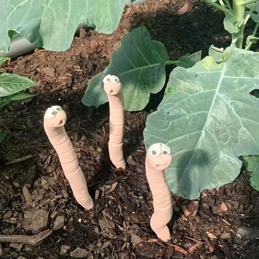 Three worm shaped water sensors poking out of the soil with leaves in the background. 