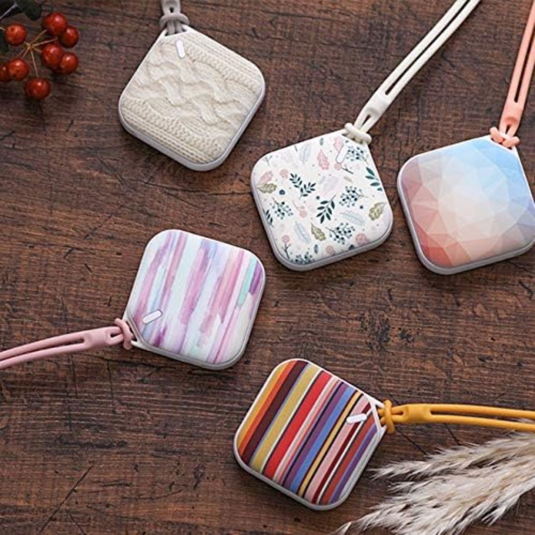 Five colorful pocket rechargeable hand warmers on a wooden surface