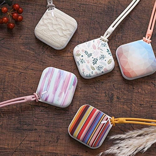 Five colorful pocket rechargeable hand warmers on a wooden surface