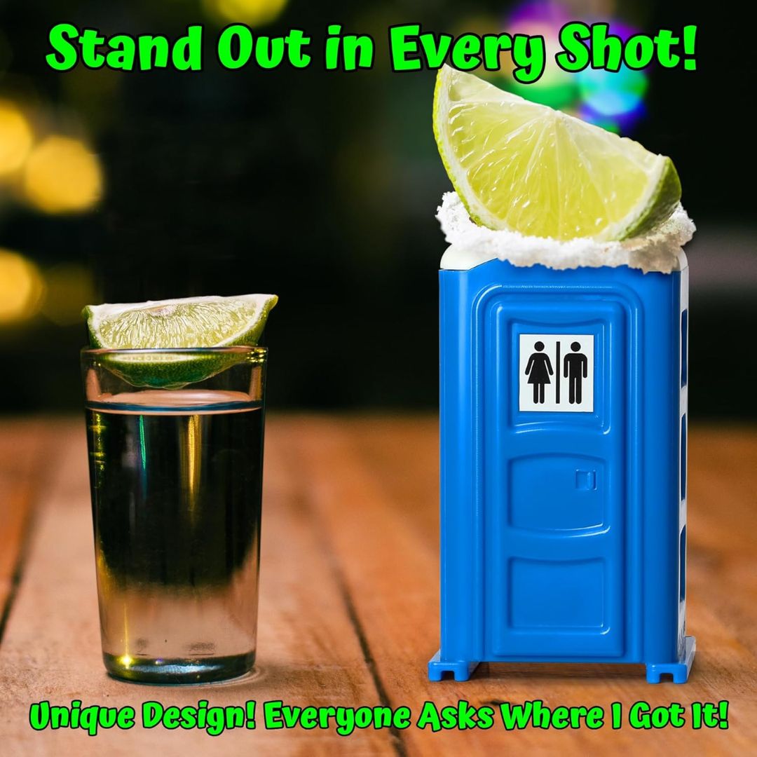 Blue portable toilet with whipped cream and lime slices next to a shot glass on a wooden surface.