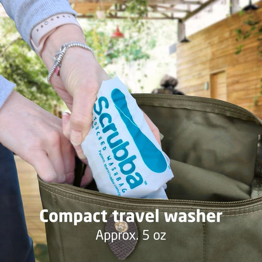 A pair of hands packing a compact portable travel washing bag into an army colored bag
