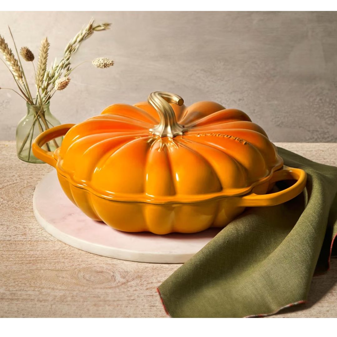 Le Creuset pumpkin cast iron braiser on a wooden background