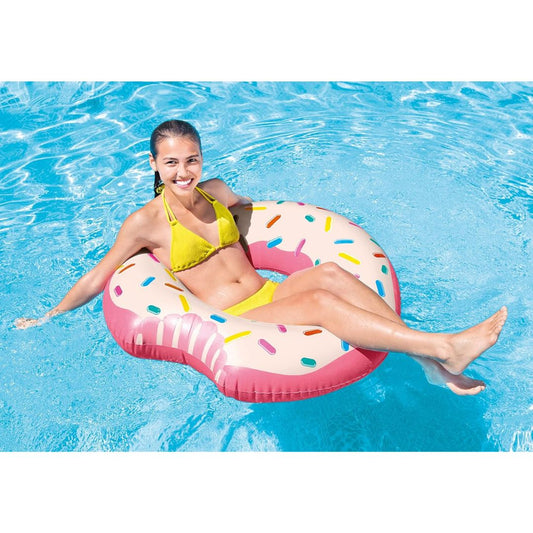 Woman in yellow bikini sitting on a pink donut-shaped inflatable pool float in clear blue water.