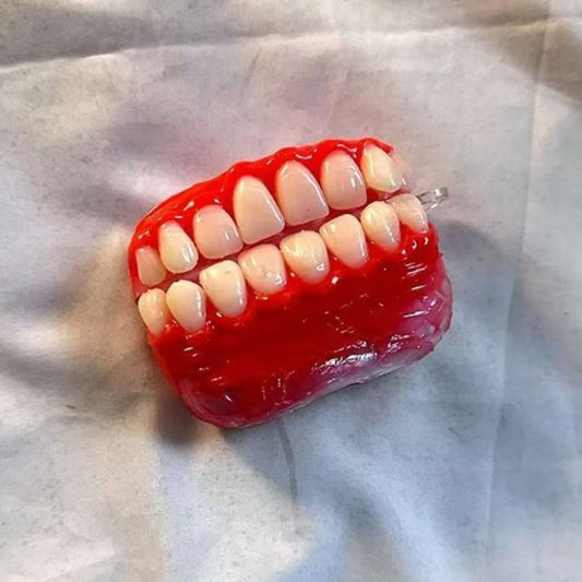 Realistic red gum and white teeth AirPods case designed to look like a set of dentures